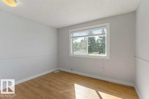 Bright room with wood-finish flooring, white baseboards, and a large window with blinds - 3736 12 Avenue, Edmonton, AB - Indoor Photo Showing Other Room