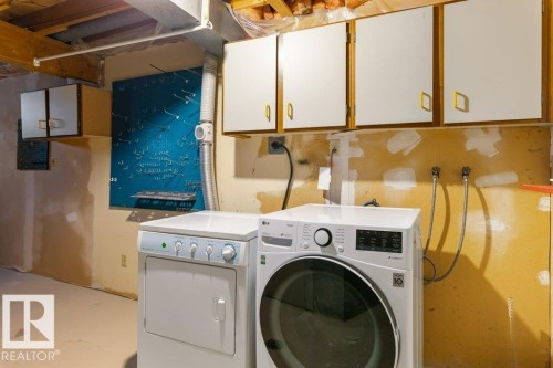 Laundry area featuring a front-load washing machine, a top-load dryer, and overhead cabinetry - 3736 12 Avenue, Edmonton, AB - Indoor Photo Showing Laundry Room