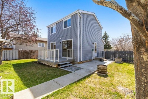 Rear exterior featuring light gray siding, a deck with white railings, a sliding glass door, and a concrete pathway - 3736 12 Avenue, Edmonton, AB - Outdoor With Deck Patio Veranda