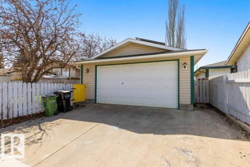Attached single-car garage featuring a white panel door, beige siding, and green trim - 3736 12 Avenue, Edmonton, AB - Outdoor With Exterior