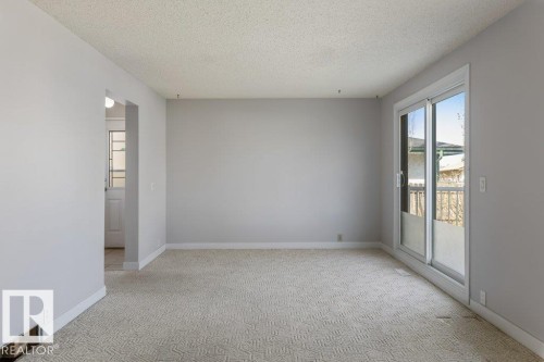Spacious interior room featuring light-toned walls, textured carpeting, and white baseboards - 3736 12 Avenue, Edmonton, AB - Indoor Photo Showing Other Room