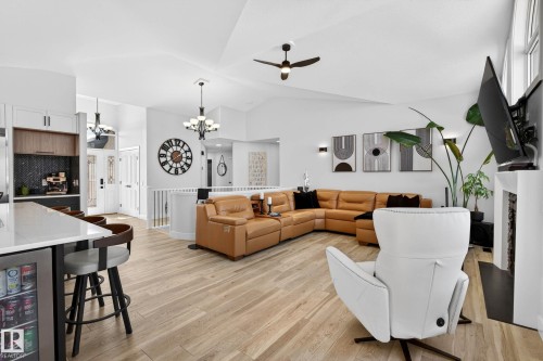 Vaulted ceiling living area featuring light wood-finish flooring, a contemporary fireplace with a mounted television, and abundant natural light from upper windows - 324 Cutts Crest, Edmonton, AB - Indoor Photo Showing Other Room