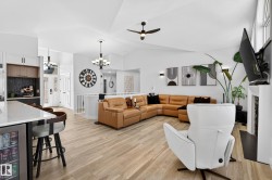 Vaulted ceiling living area featuring light wood-finish flooring, a contemporary fireplace with a mounted television, and abundant natural light from upper windows - 
