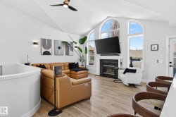 Spacious living area featuring vaulted ceilings, light wood-finish flooring, and a stone-clad fireplace - 