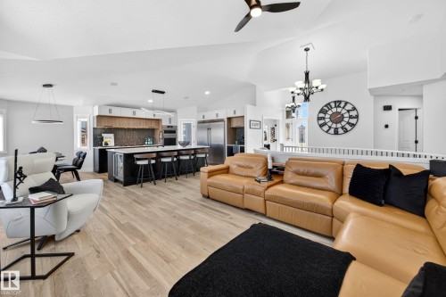 Open-concept living area featuring light wood-finish flooring, vaulted ceilings, and a contemporary kitchen - 324 Cutts Crest, Edmonton, AB - Indoor Photo Showing Living Room