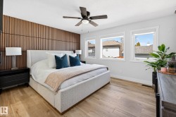 Bedroom featuring a wood-slat accent wall, three windows, and wood-finish flooring - 