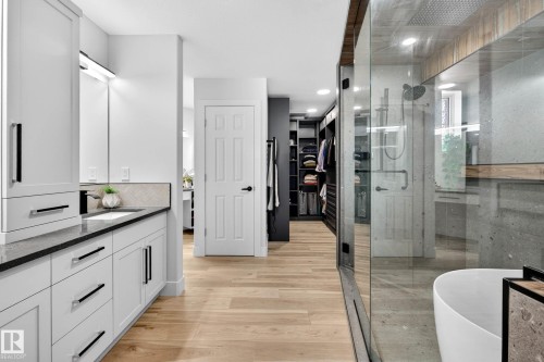 Bathroom featuring a dual vanity with white cabinetry, black countertops, and a herringbone tile backsplash - 324 Cutts Crest, Edmonton, AB - Indoor Photo Showing Bathroom