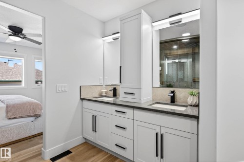 Dual vanity with dark countertops and white cabinetry - 324 Cutts Crest, Edmonton, AB - Indoor Photo Showing Bathroom