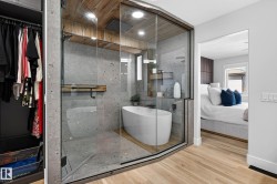 Integrated wet room featuring a freestanding soaking tub, a rainfall showerhead, and concrete-finish wall tile - 