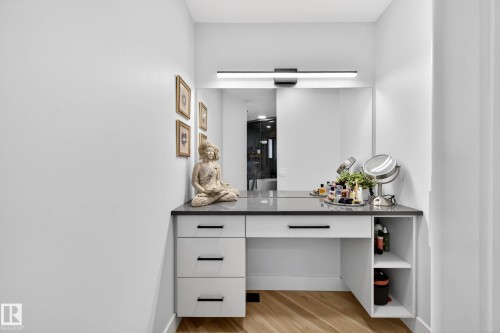 Built-in vanity with a dark countertop, white cabinetry with black hardware, integrated mirror, and overhead linear lighting - 324 Cutts Crest, Edmonton, AB - Indoor