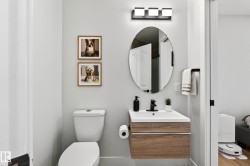 Modern bathroom featuring a floating wood-finish vanity with an integrated sink, matte black faucet, and an oval mirror - 