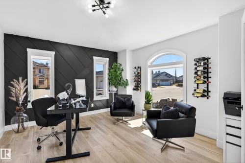 Room featuring a dark accent wall with geometric paneling, light wood-finish flooring, and a modern chandelier - 324 Cutts Crest, Edmonton, AB - Indoor