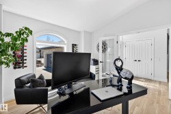 Bright interior space featuring an arched window, light wood-finish flooring, and white paneled doors - 
