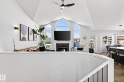 Vaulted ceiling with a ceiling fan and recessed lighting, featuring arched windows and a fireplace with a dark-toned mantel - 