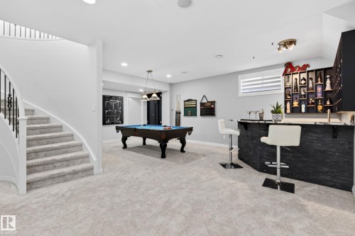 Entertainment area featuring a built-in bar with stacked stone facade and a polished countertop - 324 Cutts Crest, Edmonton, AB - Indoor