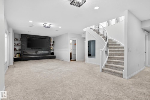 Curved staircase with black wrought iron spindles and white newel posts - 324 Cutts Crest, Edmonton, AB - Indoor
