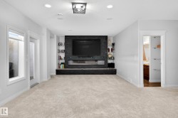 Carpeted living area featuring a built-in entertainment center with a dark stone-finish surround, an electric fireplace, and integrated shelving - 