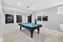 Recreation room featuring light gray walls, recessed lighting, and a dark wood billiards table with a blue felt surface - 