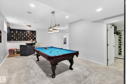 Recreation room featuring soft gray carpeting, a built-in wet bar with dark stone-finish accents, integrated shelving, and recessed lighting - 324 Cutts Crest, Edmonton, AB - Indoor Photo Showing Other Room