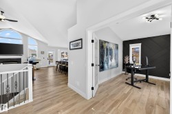 Open-concept living area with vaulted ceilings and wood-finish flooring - 