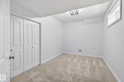 Neutral-toned carpeted room featuring a window, white walls, and bi-fold closet doors with panel detailing - 