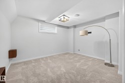 Recessed room featuring light-colored patterned carpeting, white baseboards, and a single window with horizontal blinds - 