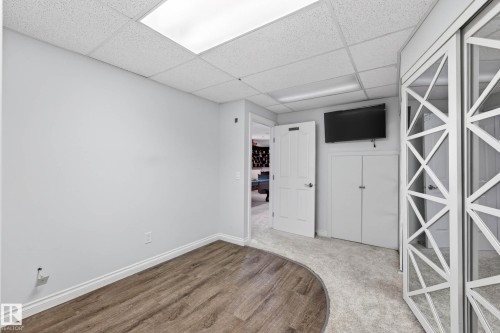 Recessed fluorescent lighting illuminates a room featuring wood-finish flooring transitioning to light gray carpeting - 324 Cutts Crest, Edmonton, AB - Indoor Photo Showing Other Room