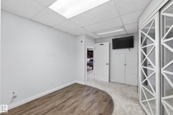 Recessed fluorescent lighting illuminates a room featuring wood-finish flooring transitioning to light gray carpeting - 