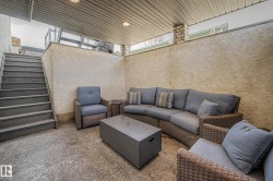 Private outdoor patio featuring a textured stucco wall, concrete flooring, and a covered ceiling with recessed lighting - 
