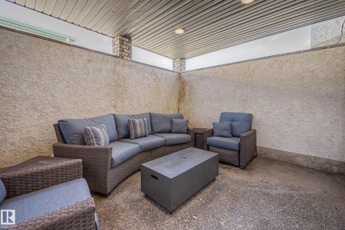 Covered patio featuring a textured stucco wall, a slatted ceiling with recessed lighting, and brick column accents - 324 Cutts Crest, Edmonton, AB - Outdoor With Deck Patio Veranda With Exterior