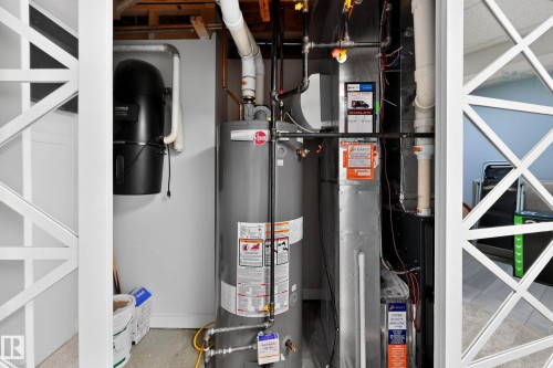 Utility area featuring a water heater, furnace system, central vacuum unit, and exposed ceiling joists - 324 Cutts Crest, Edmonton, AB - Indoor Photo Showing Basement