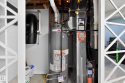 Utility area featuring a water heater, furnace system, central vacuum unit, and exposed ceiling joists - 