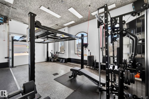 Dedicated fitness space featuring an industrial-style epoxy floor, textured ceiling, and recessed lighting - 324 Cutts Crest, Edmonton, AB - Indoor Photo Showing Gym Room