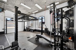 Dedicated fitness space featuring an industrial-style epoxy floor, textured ceiling, and recessed lighting - 
