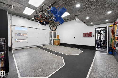Attached garage featuring a segmented overhead door with horizontal windows, epoxy flooring with defined parking areas, and recessed ceiling lighting - 324 Cutts Crest, Edmonton, AB - Indoor Photo Showing Garage