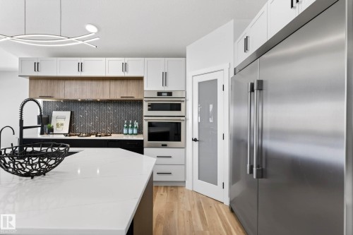 Kitchen featuring an oversized island with white countertop, black faucet, and a dual-tone cabinetry design - 324 Cutts Crest, Edmonton, AB - Indoor Photo Showing Kitchen With Upgraded Kitchen