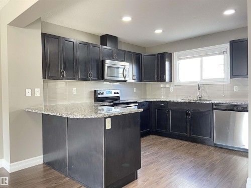 Modern kitchen featuring dark wood-finish cabinetry, light speckled countertops, a subway tile backsplash, and stainless steel appliances - 1520 105 Street, Edmonton, AB - Indoor Photo Showing Kitchen With Double Sink With Upgraded Kitchen