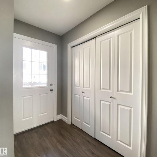 Entryway featuring a white paneled door with glass inserts, wood-finish flooring, and white bifold closet doors - 1520 105 Street, Edmonton, AB - Indoor Photo Showing Other Room