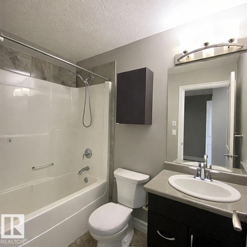 Bathroom featuring a bathtub with shower, toilet, and vanity with an integrated sink - 1520 105 Street, Edmonton, AB - Indoor Photo Showing Bathroom