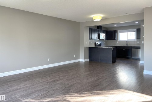 Open-concept living area featuring wood-finish flooring, neutral wall tones, and white trim - 1520 105 Street, Edmonton, AB - Indoor Photo Showing Kitchen