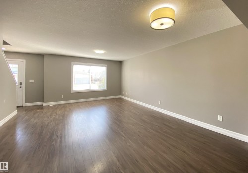 Spacious main living area featuring wood-finish flooring, neutral wall tones, and white trim - 1520 105 Street, Edmonton, AB - Indoor Photo Showing Other Room