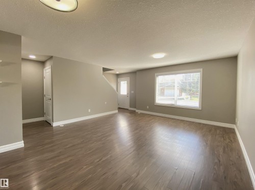 Open-concept living area featuring wood-finish flooring, neutral wall tones, and white baseboards - 1520 105 Street, Edmonton, AB - Indoor