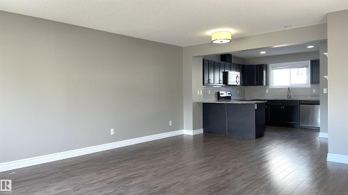 Open-concept living area with dark wood-finish flooring, light gray wall paint, and white trim - 1520 105 Street, Edmonton, AB - Indoor Photo Showing Kitchen