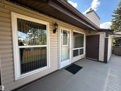 Exterior patio featuring light gray textured surface, vinyl siding, and white-framed windows - 
