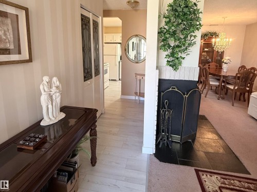 Entryway featuring light wood-finish flooring, vertical striped wallpaper, and bi-fold doors with decorative glass inserts - 2071 Saddleback Road, Edmonton, AB - Indoor