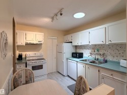 Bright kitchen featuring white cabinetry and appliances - 