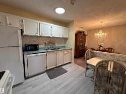 Kitchen featuring white cabinetry, light blue countertops, a double basin sink, and wood-finish flooring - 