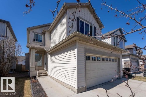 Two-story property featuring light-toned siding, an attached double-door garage with transom windows, and a covered front entry with columns - 1734 63A Street, Edmonton, AB - Outdoor