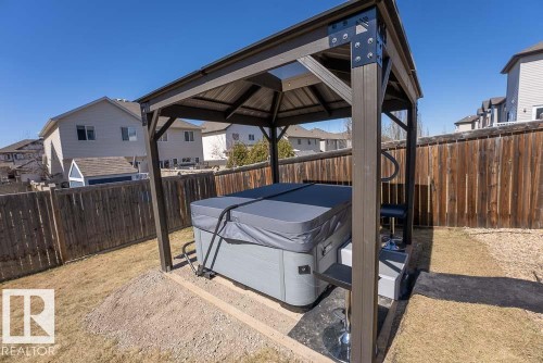 Covered outdoor hot tub featuring a durable gray cover, integrated steps, and a permanent dark brown gazebo structure with a metal roof - 1734 63A Street, Edmonton, AB - Outdoor With Exterior