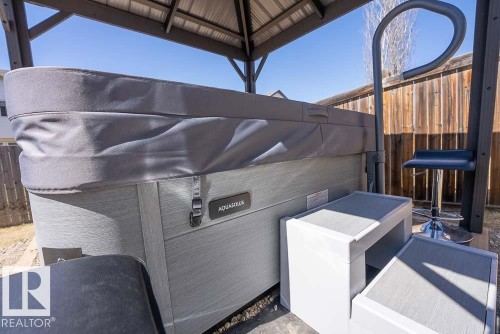 Outdoor spa with a protective cover, flanked by a privacy fence and a metal gazebo - 1734 63A Street, Edmonton, AB - Outdoor With Exterior